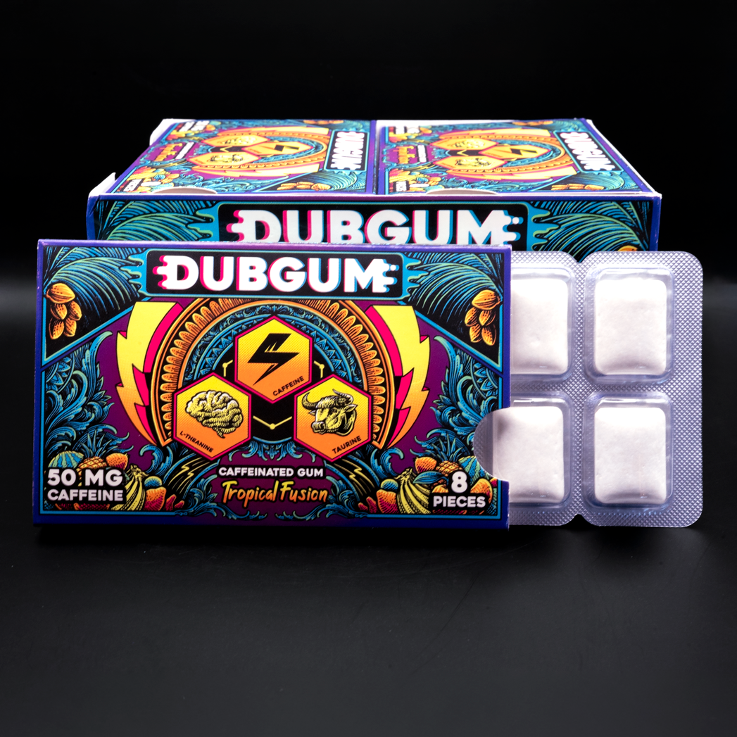 12 pack box of Dubgum Tropical fusion caffeine gum alongside two blister packs containing white square gum pieces, set against a dark black background.