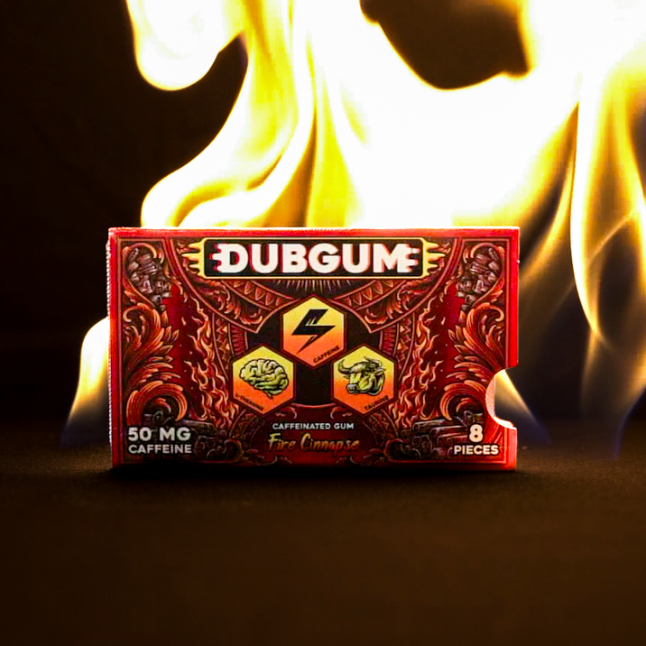 A red and black Dubgum Fire cinnamon flavor packaging box sits on a dark surface with bright yellow and orange flames rising behind it against a black background.